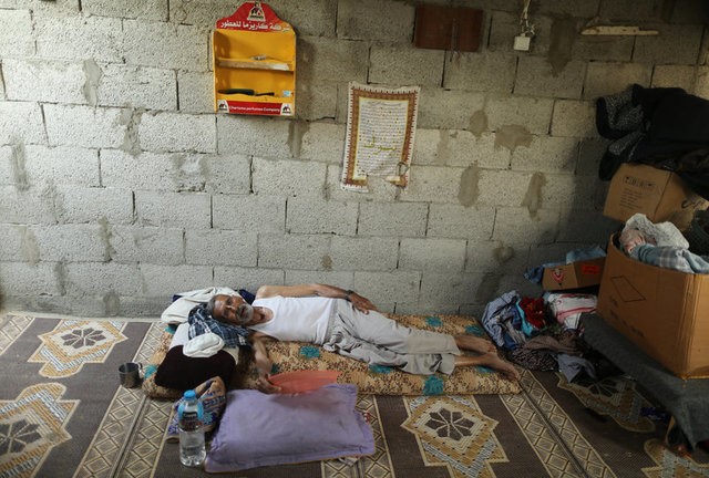 A Palestinian man uses a plastic tray to cool himself from the heat during power cut in his house in Khan Younis, in the southern Gaza Strip, July 3, 2017. 