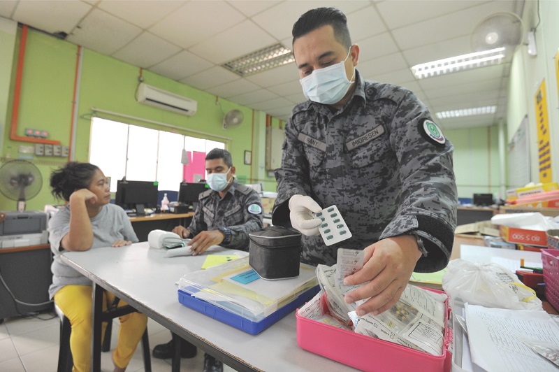 A detainee receives medical treatment from two Immigration officers after complaining of cough. — Picture by Mukhriz Hazim