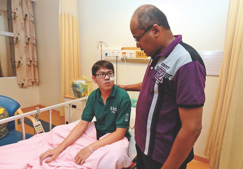 Headmaster T. Gunalan consoling Sam Ming Hui who was lucky to escape with just a gash to his cheek. u00e2u20acu201d Picture by Farhan Najib