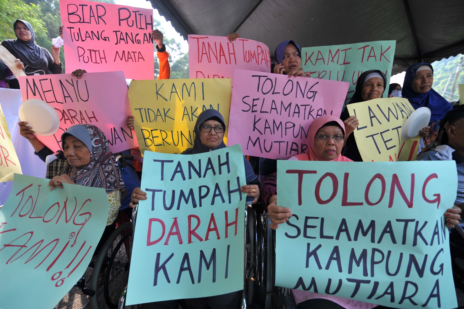 Residents holding placards during the protest at Kampung Mutiara today.