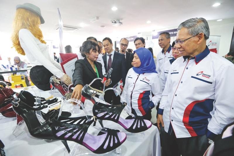 Mustapa (right) and Nancy listen as Mestrae founder Christine Pamela Chandrakasan explains how the shoes with interchangeable heels work. u00e2u20acu201d Picture by Ahmad Zamzahuri