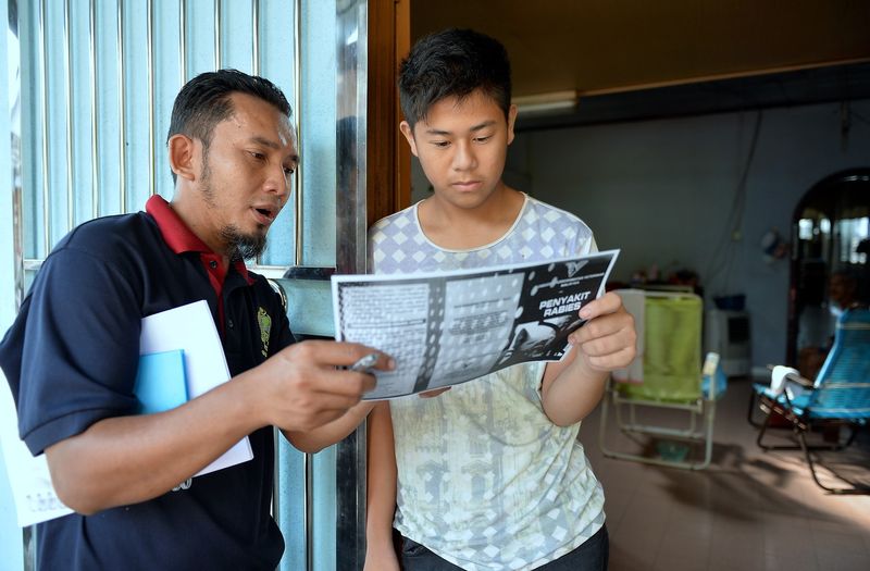 Taiping veterinary office personnel Zulkifli Muhammad Fuzi (left) explaining to a resident about the rabies epidemic, in Bukit Gantang, July 17, 2017. Earlier two girls aged 11 and 12 in Kuala Sepetang were bitten by their pet dog before the animal died e