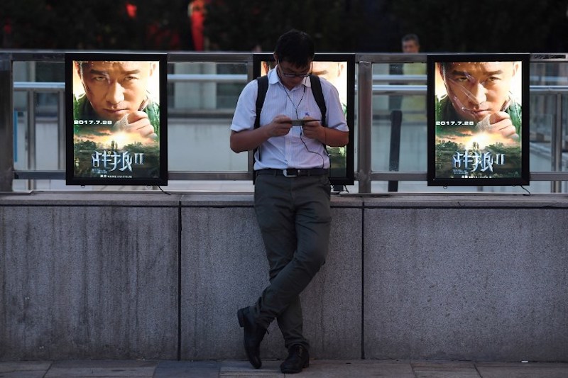 A man stands in front of movie posters for u00e2u20acu02dcWolf Warriors 2u00e2u20acu2122 in Beijing August 7, 2017. u00e2u20acu201d AFP pic