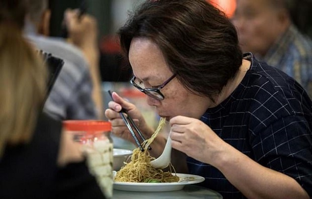 A woman eats a bowl of noodles, handmade using a traditional bamboo pole technique, at a restaurant in Hong Kong. u00e2u20acu201d AFP pic