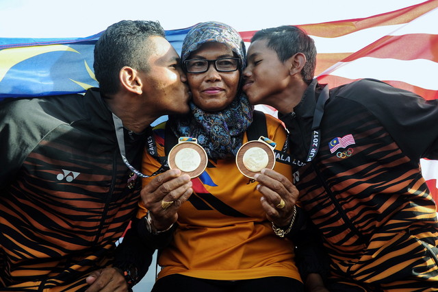 National sailing athletes Muhammad Fauzi Kaman Shah (right) and elder brother Ahmad Latif Khan kiss their mother Hasni Mohamed after winning respective gold medals at Langkawi National Sailng Centre today. u00e2u20acu201d Bernama pic
