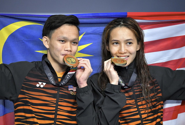 Malaysia's divers Leong Mun Yee (right) and Jellson Jabillin show off their medals after winning gold in the mixed synchronised 10M Platform final during prize giving ceremony of the 29th SEA Games at National Aquatic Centre in Bukit Jalil today. u00e2u20acu201d Bern