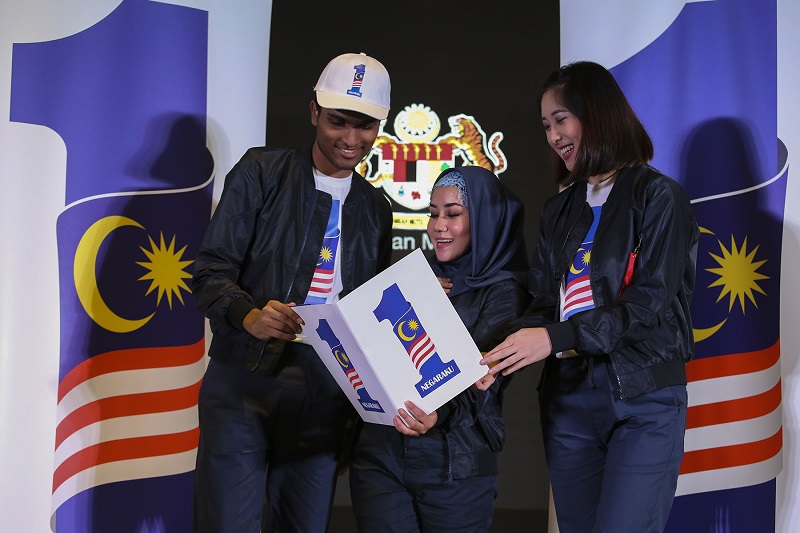 (From left) Theeban Mahendran, Siti Hasreena Rosli and Yvonne Lee Hui Lee of the Lim Kok Wing Choir looking at the new 1Malaysia Negaraku logo during the launch event in Putrajaya August 23, 2017. 
