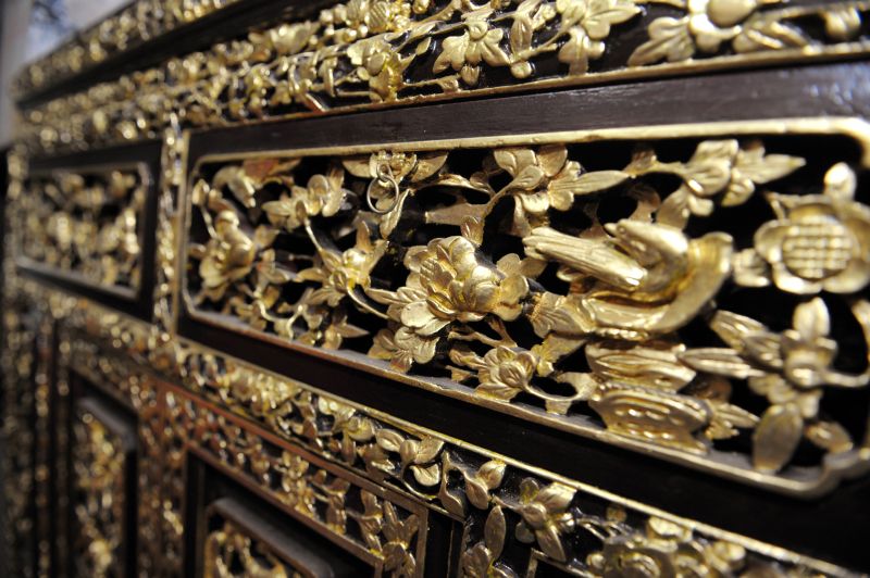 These gold motifs on a Peranakan furniture are not painted but each are painstakingly layered with gold leaf by Yuen.