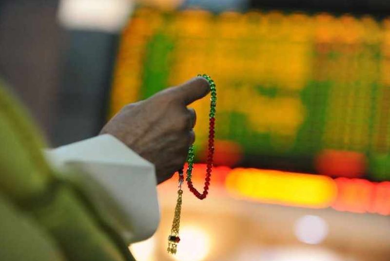 File picture shows an investor holding the tasbeeh as he monitors electronic boards displaying stock information at the ADX Abu Dhabi Securities Exchange stock market. u00e2u20acu201d Reuters pic