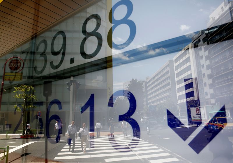 People are reflected on an electronic board showing Japan's Nikkei average outside a brokerage at a business district in Tokyo August 14, 2017. u00e2u20acu201d Reuters picnn