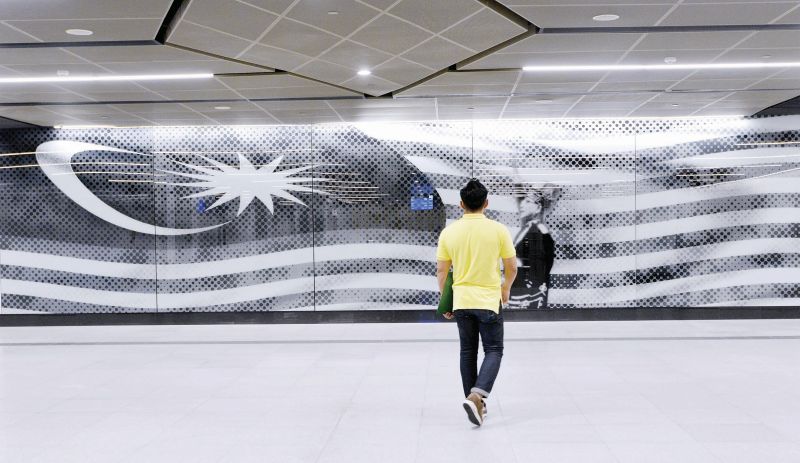 A commuter looks at the iconic photo of Tunku Abdul Rahman. u00e2u20acu201d Malay Mail pic