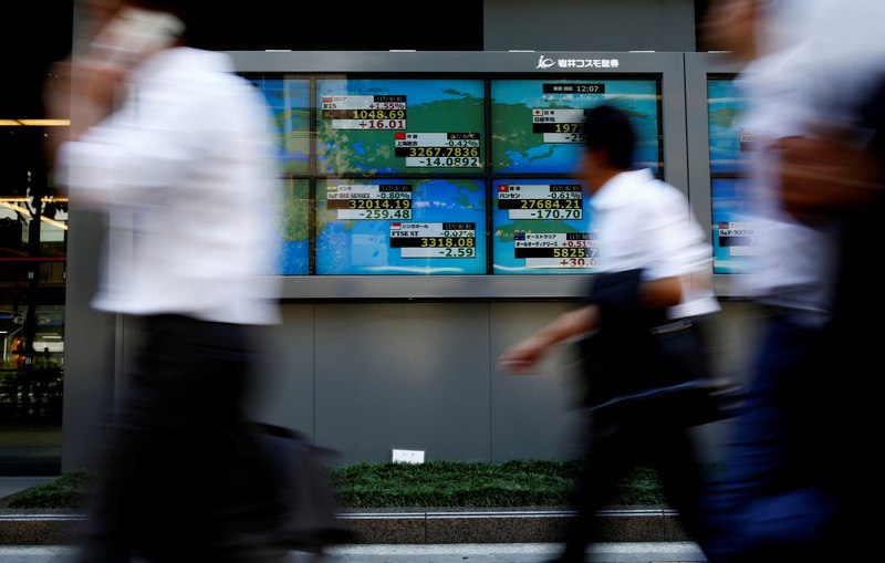 People walk past an electronic board showing Japan's Nikkei average outside a brokerage at a business district in Tokyo August 9, 2017. u00e2u20acu201d Reuters pic