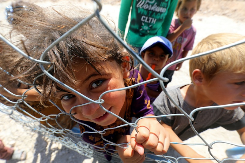 Displaced children from the Islamic State group's Syrian stronghold of Raqa, pose for a photo behind a fence at a camp in Ain Issa on August 22, 2017. u00e2u20acu201d AFP pic 