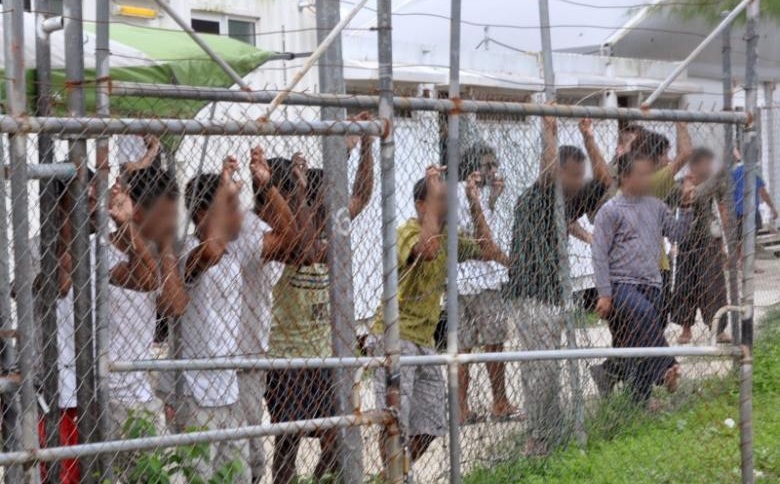 Asylum-seekers look through a fence at the Manus Island detention centre in Papua New Guinea March 21, 2014. Eoin Blackwell/AAP/via Reuters