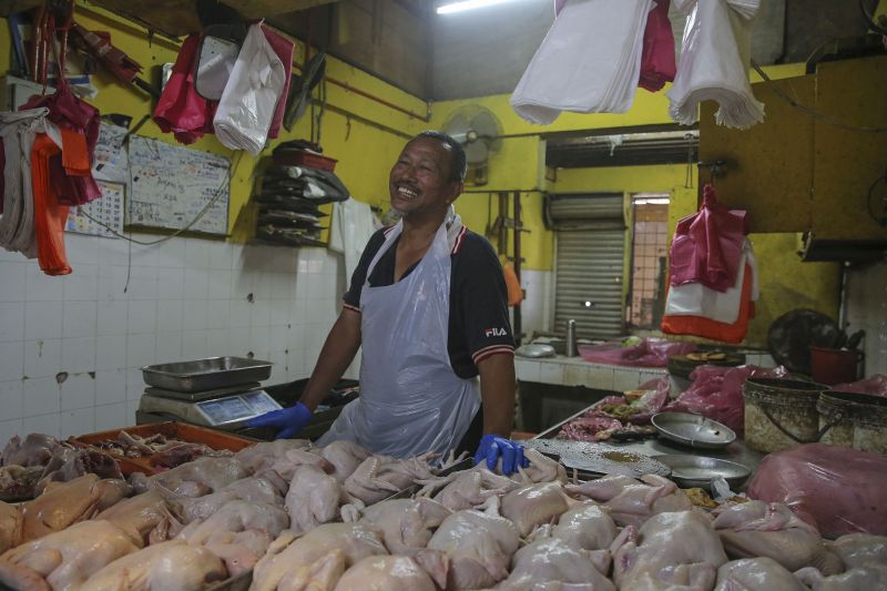 Poultry seller Mohd Noor Dol smiles as he works at his stall in a wet market in Port Klang.