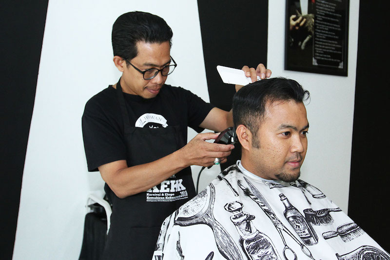 TN Winda Mohd Tahir, owner of BlackWhite Barbershop, attends to a customer.  — Picture by Miera Zulyana