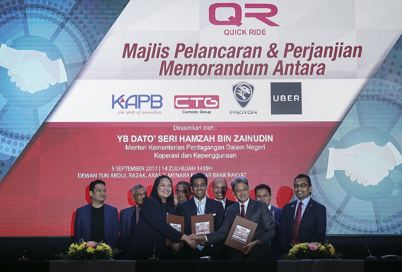 (Front row from left ) General Manager of Expansion UBER Karina Ali Noor, CEO of Quick Ride Mohamed Fahmi Mohamed Ilyas and CEO of Proton Holdings Datuk Ahmad Fuaad Mohd Kenali exchange documents during a MoU signing ceremony at Menara Kembar Bank Rakyat 