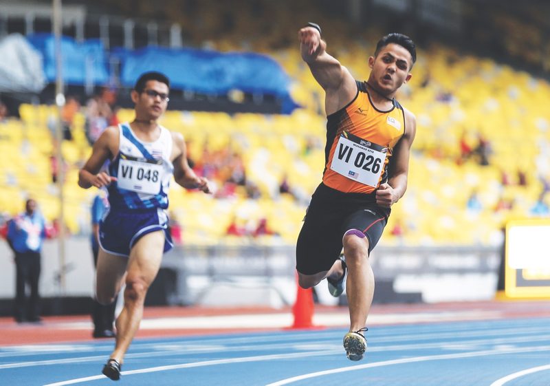 Afiq celebrates his 100m T12 victory in style. u00e2u20acu201d Picture by Azneal Ishak