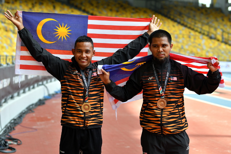 Malaysian athlete Mohamed Erwan Mohd Hasnoor (left) and Amir Firdaus Jamaluddin pose with the national flag after winning the gold and bronze medal respectively in the 9th Asean Para Games in Kuala Lumpur September 19, 2017. u00e2u20acu201d Bernama pic