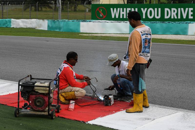 Workers repair a drain cover after Haas F1's French driver Romain Grosjean suffered a frightening tyre explosion at the Sepang F1 circuit September 29, 2017. u00e2u20acu201d AFP picn