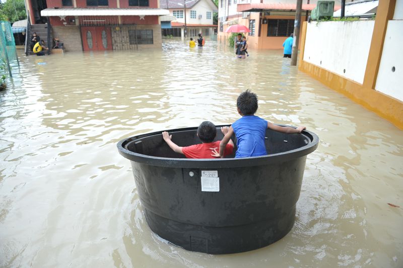 Children use an empty water tank as a makeshift boat during the flood at Jalan Perak, September 15, 2017. u00e2u20acu2022 Picture by KE Ooi