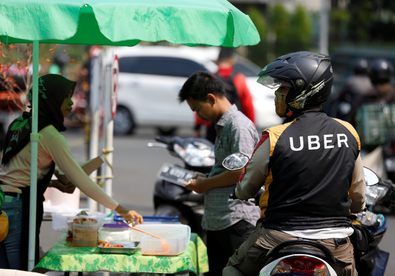 An Uber motorcycle taxi driver stops at a food stall next to a shopping mall in Jakarta September 20, 2017. u00e2u20acu201d Reuters pic