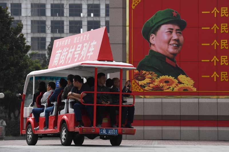 Visitors ride a tourist cart past a billboard image of late communist leader Mao Zedong at a culture centre in Nanjie village, in China’s central Henan province, September 27, 2017. — AFP pic