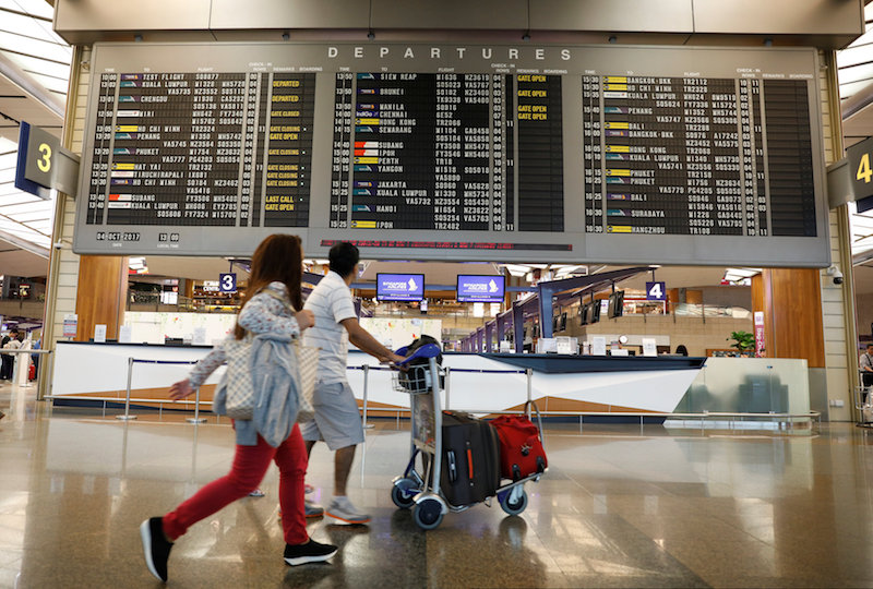 People pass a departures flight information board at Changi Airportu00e2u20acu2122s Terminal Two in Singapore October 4, 2017. u00e2u20acu201d Reuters pic
