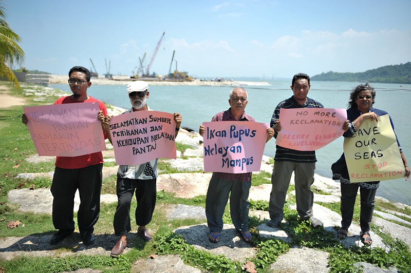 Mohd Maidin (second from left) and SAM members hold up placards in protest of land reclamation works in Penang.
