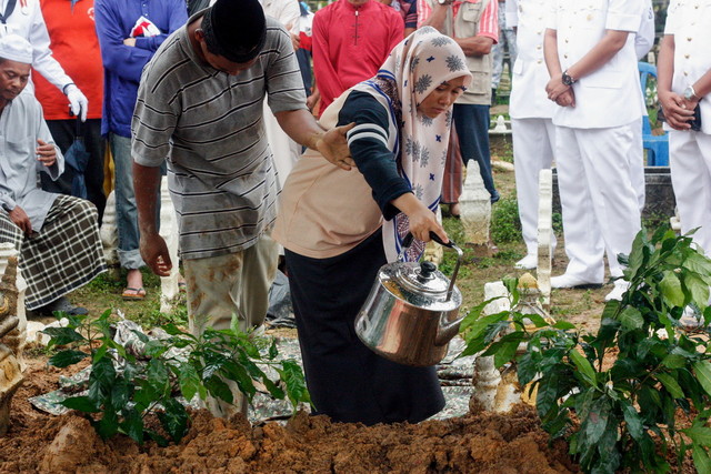 Noor Laila Afini, 19, menyiram air mawar di atas pusara abangnya Allahyarham LK 1 Muhammad Lailatulman Mohd Sukri, 26, yang selamat dikebumikan di Tanah Perkuburan Islam Rantau Panjang, 1 Okt 2017. u00e2u20acu201d Foto Bernama