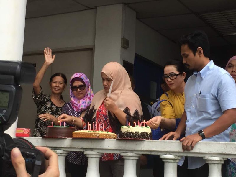 Shafieu00e2u20acu2122s wife Datin Shuryani Shaib (in beige headscarf) and their son, Mohd Shezwi Shafie (right, in blue shirt) light candles on the birthday cakes to share with the Semporna MP's supporters gathered outside the courthouse.