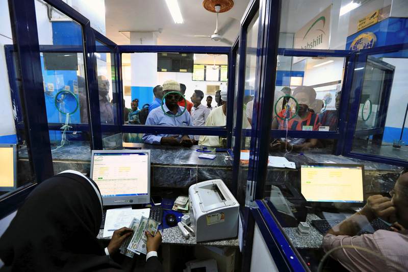 A cashier counts US dollars as people wait to receive money inside Bab Al-Mandab Exchange transfer money bureau in Khartoum, Sudan October 7, 2017. u00e2u20acu201d Reuters pic 