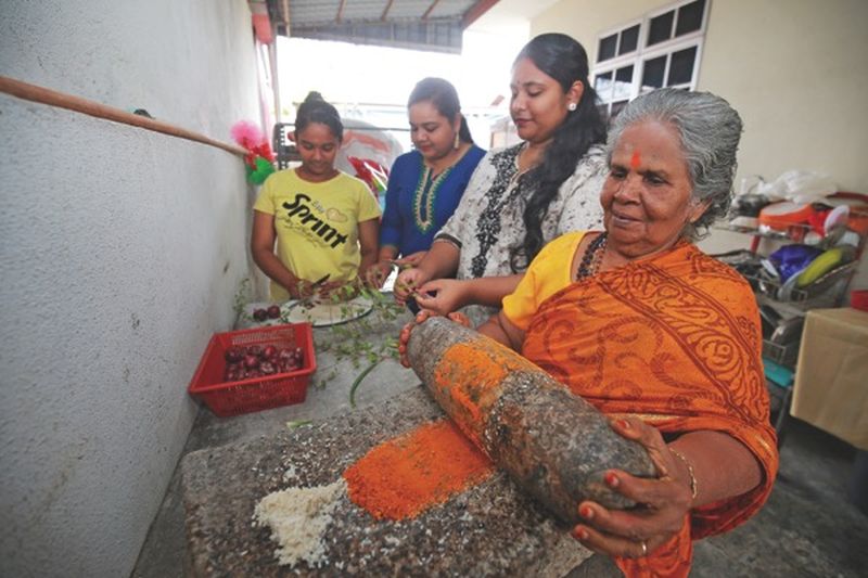 Letchumy is assisted by family members as she prepares u00e2u20acu02dcmasalau00e2u20acu2122 the traditional way using her trusted grindstone. u00e2u20acu201d Picture by Marcus Pheong