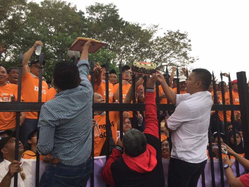 Birthday cakes brought by Shafie’s wife Datin Shuryani Shaib are shared among Parti Warisan Sabah supporters waiting outside the courthouse.