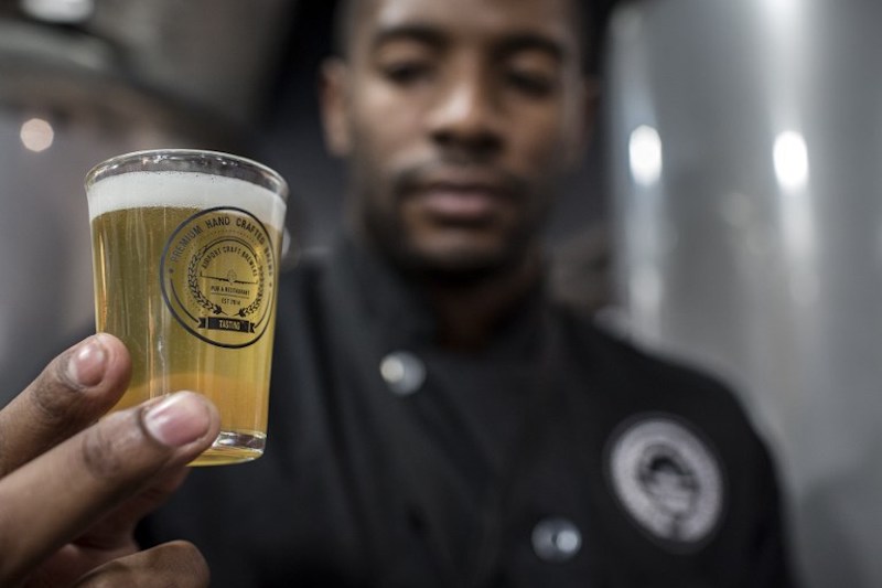Airport Craft Brewers Assistant Brewer, Brain Skosana Jr holds a glass of the Blonde Brew inside the brew house at OR Tambo International Airport in Johannesburg October 17, 2017. u00e2u20acu201d AFP pic
