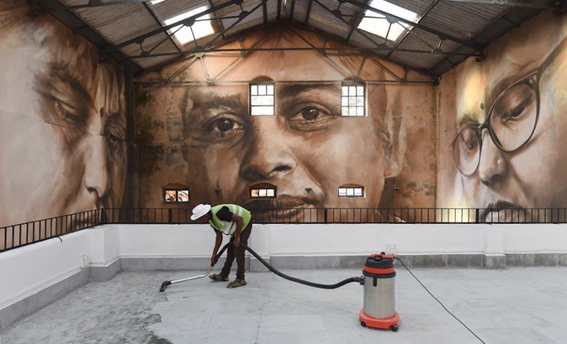 A worker cleans the viewing area in front of a photo mural of the St+art Festival at Sassoon Dock, one of the oldest fishing docks in Mumbai, November 9, 2017. — AFP pic