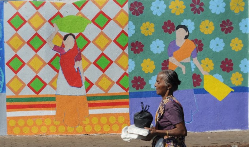 A fisherman walking past a wall painting of the St+art Festival at Sassoon Dock, one of the oldest fishing docks in Mumbai, November 9, 2017. u00e2u20acu201d AFP pic