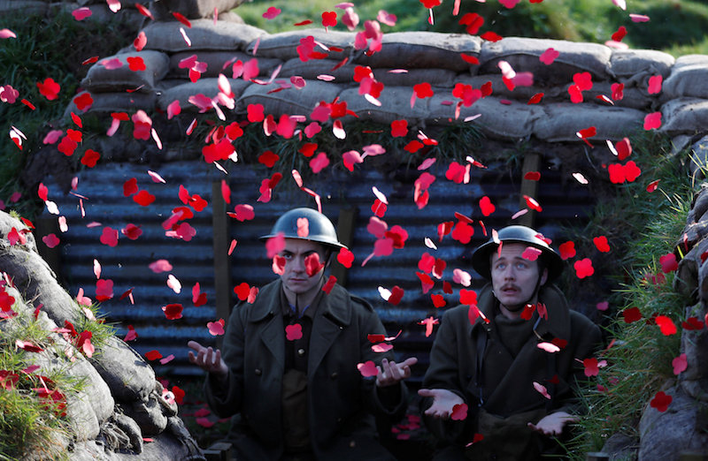 Actors Jake Morgan and Sam Ducane extend their hands to catch poppies, as they pose for photographs at the launch of the 1918 Poppy Pledge in a re-creation of a First World War trench at Pollock House in Glasgow November 10, 2017. u00e2u20acu201d Reuters pic