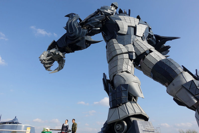 Staff members stand underneath a giant robot statue at the Oriental Science Fiction Valley theme park in Guiyang, Guizhou province, China November 24, 2017. — Reuters pic