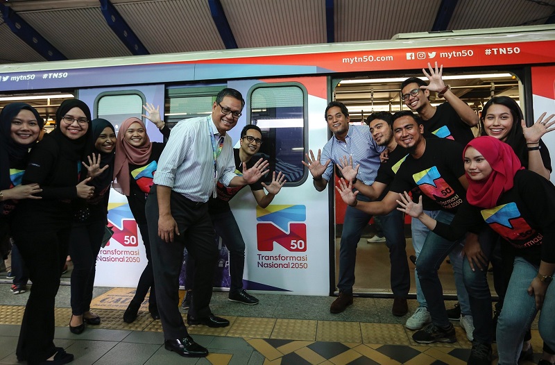 Khairy and Azmi with Prasarana Berhadu00e2u20acu2122s TN50 youth ambassadors in front of the decorated four-coach LRT train at the Bank Rakyat-Bangsar LRT station. u00e2u20acu201d Picture by Azneal Ishakn n