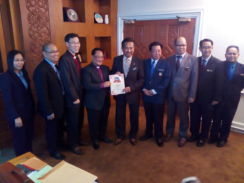 Sabah Bishop Melter Jiki Nais presents an invitation to the annual Kota Kinabalu Christmas celebration to Chief Minister Tan Sri Musa Aman. u00e2u20acu201d Picture by Julia Channn