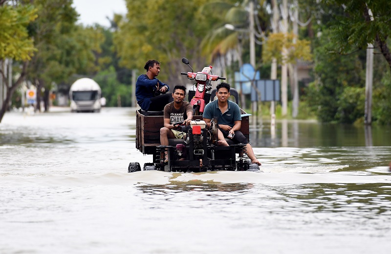 Penduduk menggunakan jentera pembajak yang diubah suai sebagai pengangkutan meredah air banjir di Jalan Kuala Terengganu-Kota Bharu di Tembila yang masih ditutup kepada kenderaan ringan akibat banjir di Besut 29 November, 2017. u00e2u20acu201d Bernama pic
