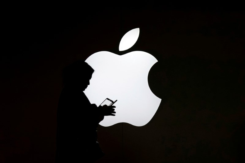 A woman looks at the screen of her mobile phone in front of an Apple logo outside its store in Shanghai July 30, 2017. u00e2u20acu201d Reuters pic