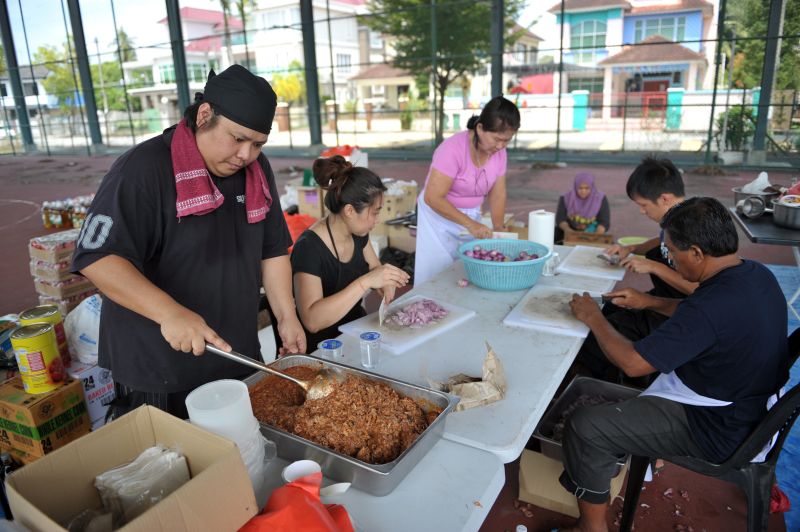 Mohd Al-Hafiz Mohd Zam (left) and other volunteers preparing food at the makeshift Kembara Kitchen in a futsal court in Sungai Dua.