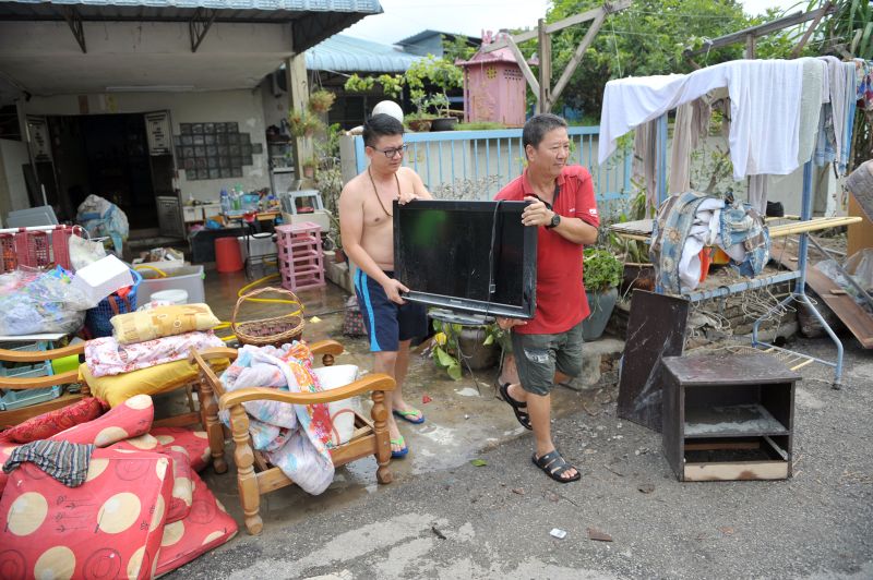 Leong Chee Meng (right) and son, Adam Leong, throwing out all of their muddied and broken furniture in Taman Seri Rambai. u00e2u20acu2022 Picture by KE Ooi