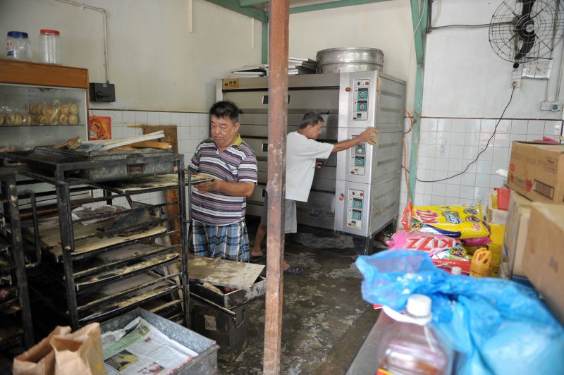 Tan Chor Huat of Kedai Biskut Hoe Heong cleaning his shop that was inundated in flood waters in the weekend.