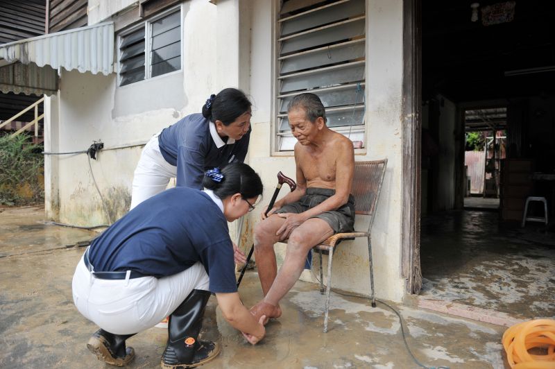 Tzu Chi Society volunteers helping to wash Tho You Seng's feet at his house.
