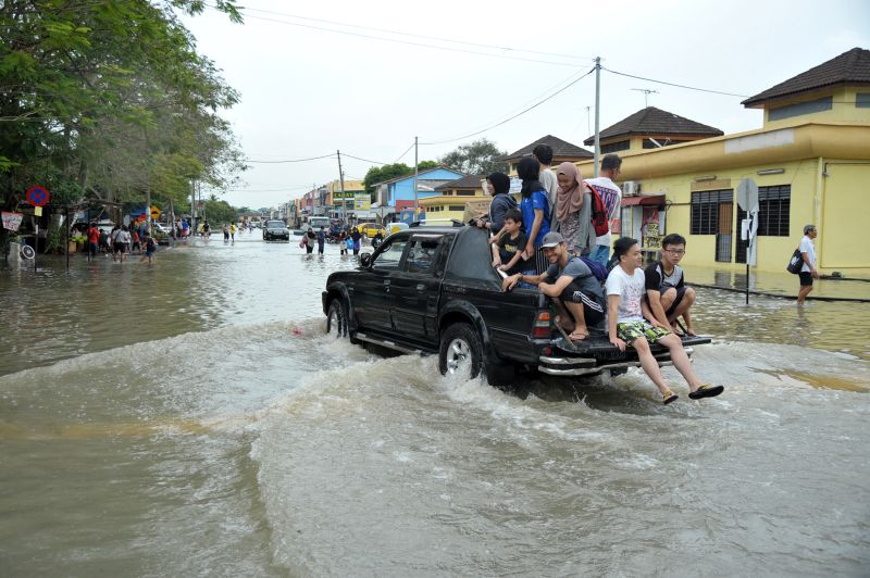 A Mitsubishi Storm is pictured ferrying residents away from their homes with Norlita (in black tudung at the front) giving directions to the driver.