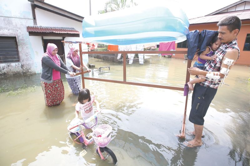 Nurul (left), Zarah and Mohd Gazi move some belongings to higher ground at Kampung Tanjung Putus. u00e2u20acu201d Picture by Azinuddin Ghazali