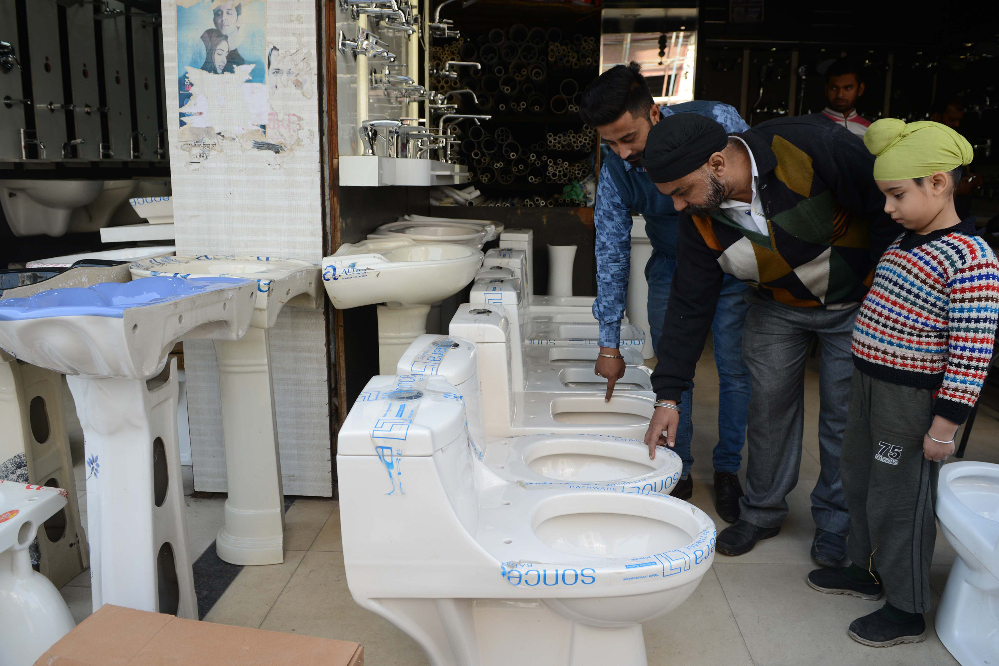 An Indian shopworker shows toilets to customers on the eve of the 'World Toilet Day' in a hardware shop in Amritsar on November 18, 2017. u00e2u20acu201d AFP pic